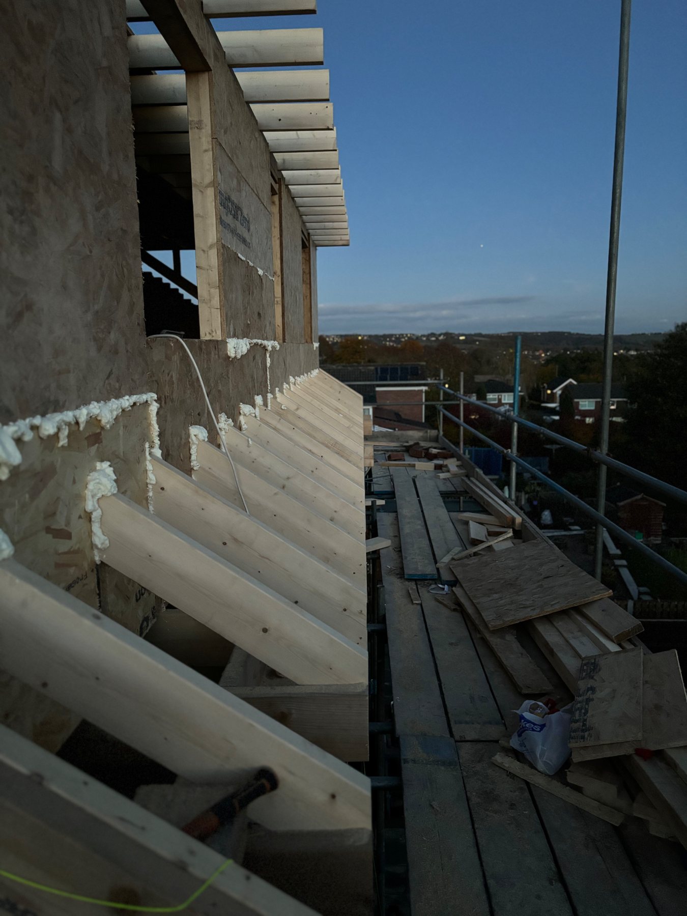 Rafter feet projecting from a sheathed timber frame seen from the scaffold