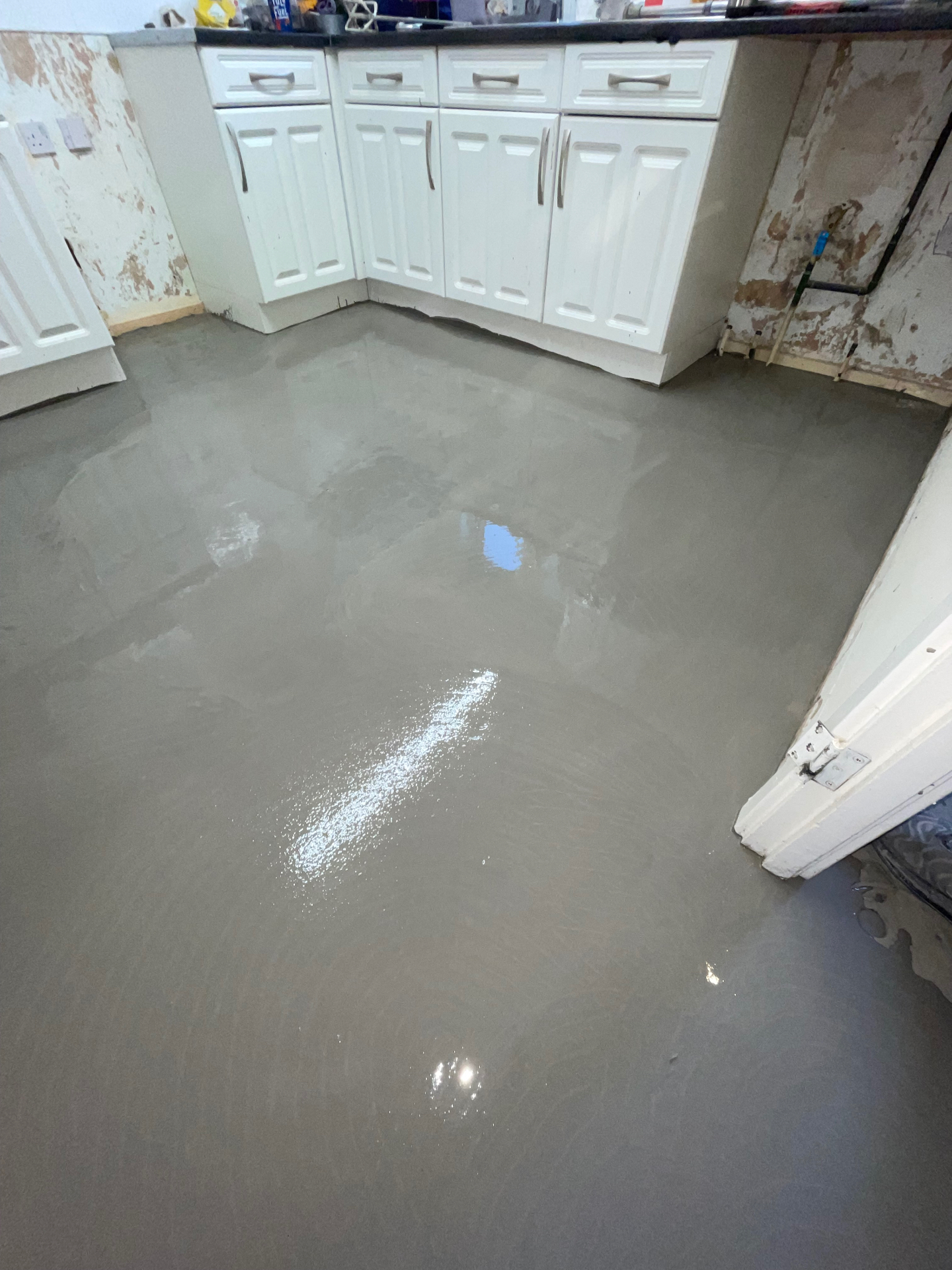 Self-levelling compound being poured over underfloor heating pipework