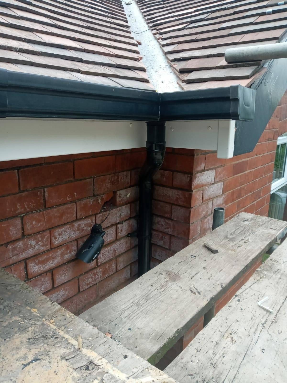 Finished tiled valley meeting black square-line guttering and downpipe